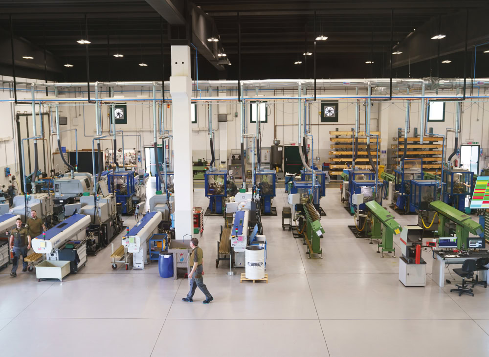 Overview of the Eredi Baitelli turning department with bar-fed automatic lathes, bar stock racks and an inspection station