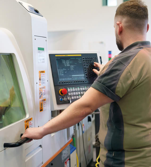 Operator programming a CNC lathe at the control panel