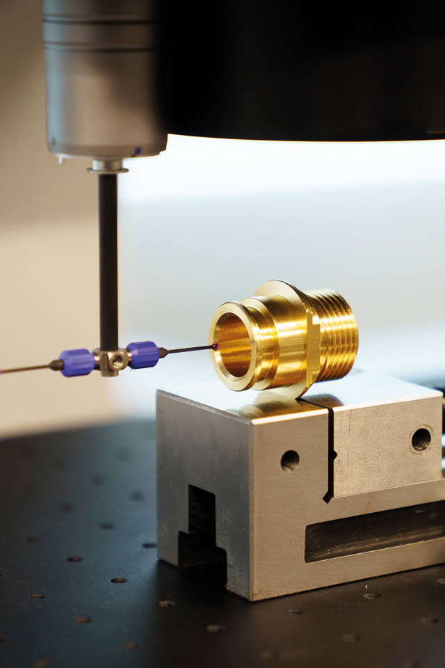 Coordinate measuring machine probe checking a turned brass fitting held in a precision vise