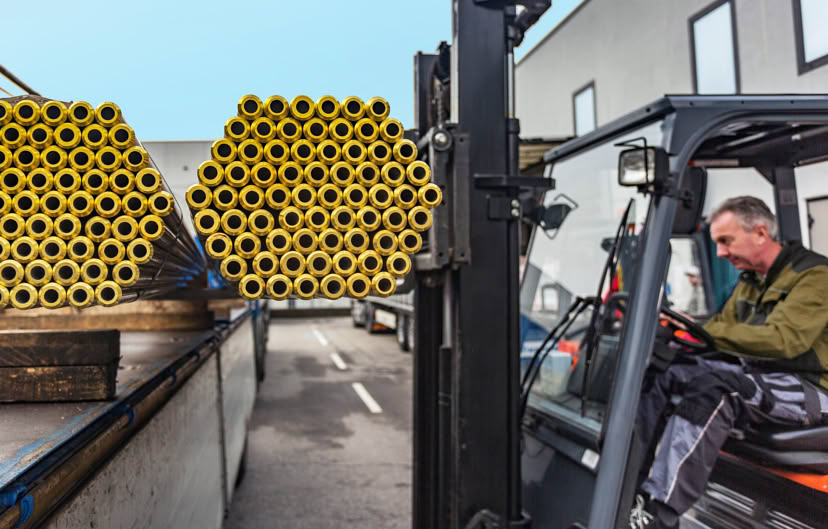 Forklift operator handling bundles of metal bars at the loading dock