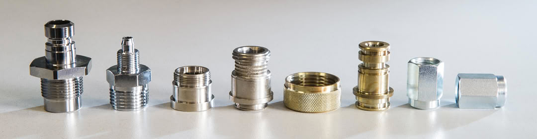 Row of turned fittings, bushings and nuts with chrome, nickel, zinc and natural brass finishes